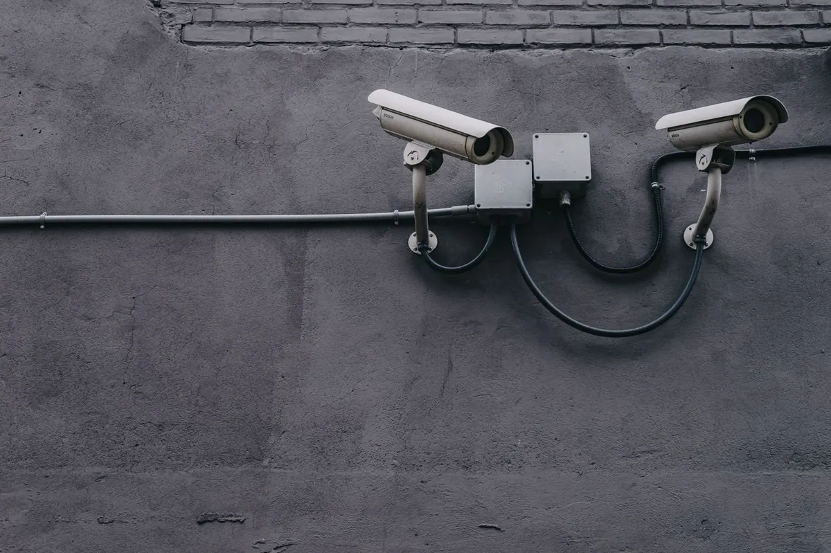 Two white CCTV cameras mounted on an exterior wall